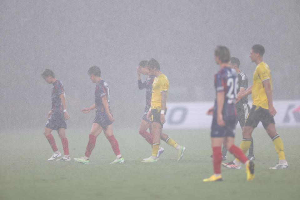 雷の危険で引き揚げる両チームイレブン（撮影・西岡正）