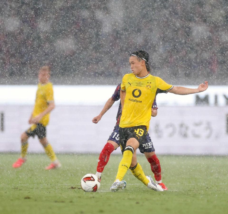 　前半、激しい雨の中を競り合うドルトムント・山本（撮影・西岡正）