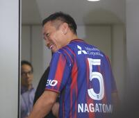 ＦＣ東京の背番号５のユニホームに袖を通し笑顔の長友佑都（撮影・吉澤敬太）