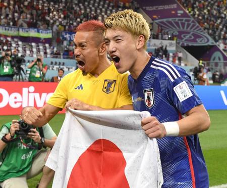 　国旗を手に雄たけびをあげる堂安と長友（撮影・金田祐二）