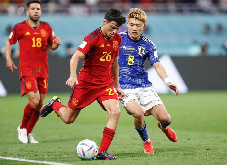 　スペインの後半、ペドリ（中央）と競り合う堂安＝１日、ドーハ（共同）