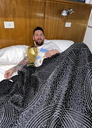 　サッカー・ワールドカップ（Ｗ杯）の優勝トロフィーと一緒にベッドで横になるアルゼンチン代表のメッシ選手＝２０日公開（メッシ選手のインスタグラムより、ロイター＝共同）