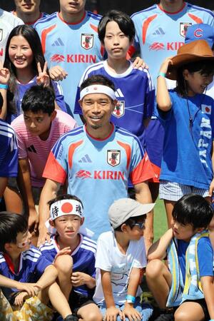 “おそろい”の日の丸バンド姿の子どもと笑顔で撮影する長友佑都（中央）