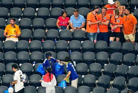 日本－オランダ　試合終了後、ごみ拾いをする日本サポーター（下）＝ダラス（共同）