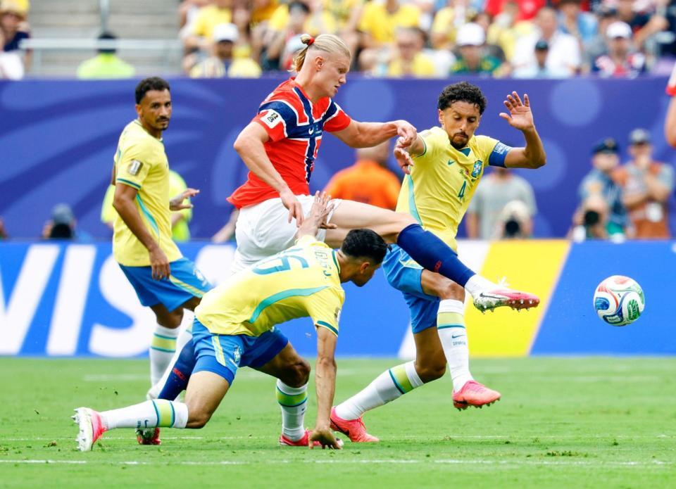 前半、競り合うノルウェーのハーランド（上）とブラジルのマルキーニョス（右）＝共同