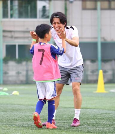 ミニゲームで得点を決めた子どもとタッチを交わす中村敬斗（撮影・石井剣太郎）