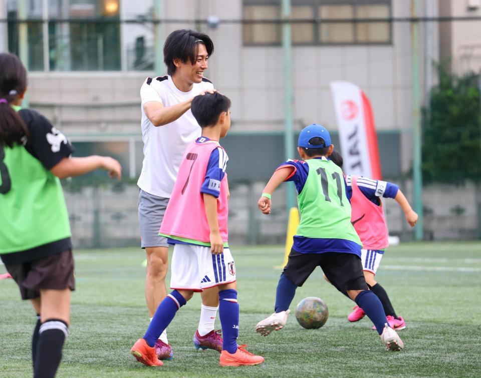 ミニゲームで得点を決めた子どもの頭をなでる中村敬斗（撮影・石井剣太郎）