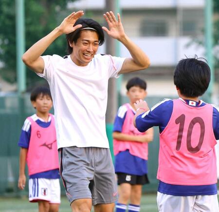 　ミニゲームで得点を決めた子どもと笑顔でタッチを交わす中村