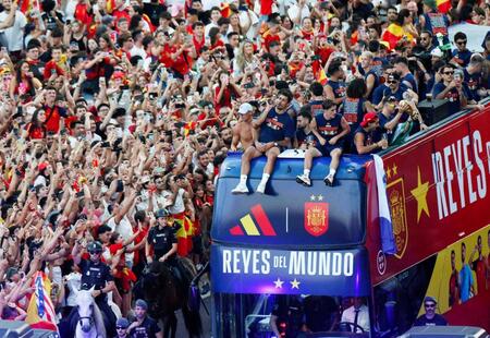 　サッカーＷ杯優勝を祝うパレードでバスに乗るスペイン代表の選手らと祝福する沿道の市民ら＝２０日、マドリード（ロイター＝共同）