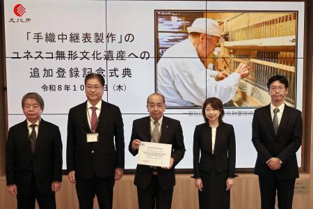 　「伝統建築工匠の技」に「手織中継表製作」が追加登録され、認定書を手にする文化財畳技術保存会の磯垣昇理事長（中央）ら＝１日午後、京都市