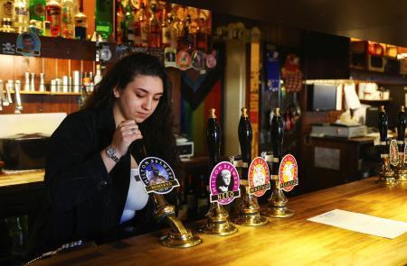 　酒を注ぐパブの従業員＝２０２３年１月、英国ケンブリッジ（ロイター＝共同）