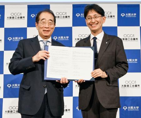 　包括連携協定の調印式で写真に納まる大商の鳥井信吾会頭（左）と大阪大の熊ノ郷淳学長＝２８日午後、大阪市