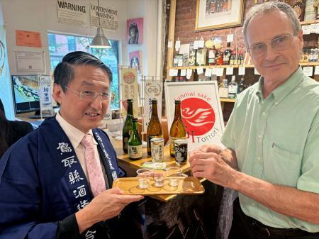 　米ニューヨーク・ブルックリンの酒店で行われた試飲会で鳥取県の日本酒を振る舞う平井伸治知事（左）＝２日（共同）