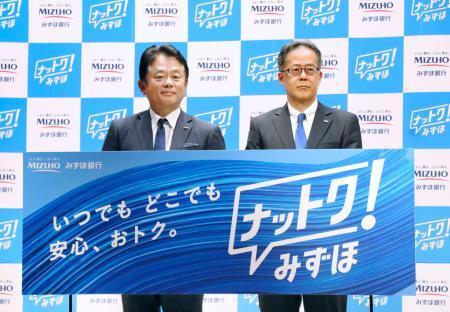 　記者会見でボードを手にする、みずほ銀行の加藤勝彦頭取（左）＝７日午前、東京都千代田区