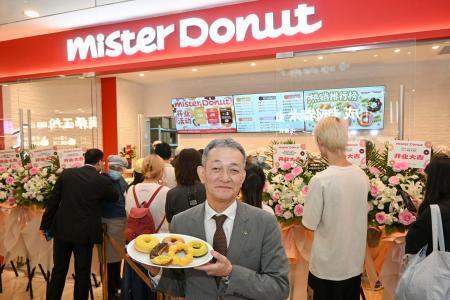 　上海のミスタードーナツの店舗前で商品を手にするダスキンの大久保裕行社長＝２８日（共同）