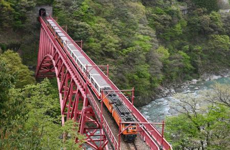 　一部区間で運行を再開し、鉄橋を渡る黒部峡谷鉄道のトロッコ電車＝１９日午前、富山県黒部市
