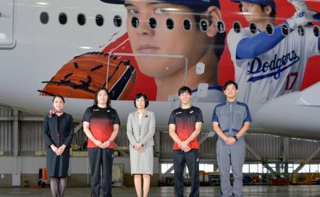 　大谷翔平選手のデザインを施した日航の特別塗装機「ＤＲＥＡＭ　ＳＨＯ　ＪＥＴ」（奥）のお披露目イベントに参加した（左２人目から右へ）陸上やり投げの北口榛花選手、鳥取三津子社長、フェンシングの加納虹輝選手＝２８日午後、羽田空港