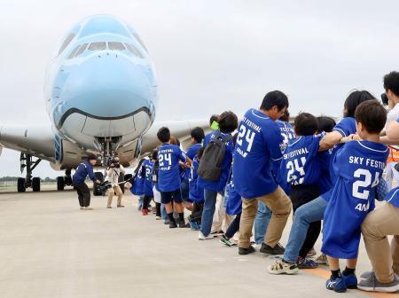 　成田空港で行われたイベントで、世界最大のジェット旅客機を綱で引っ張る小学生と保護者ら＝６日午前