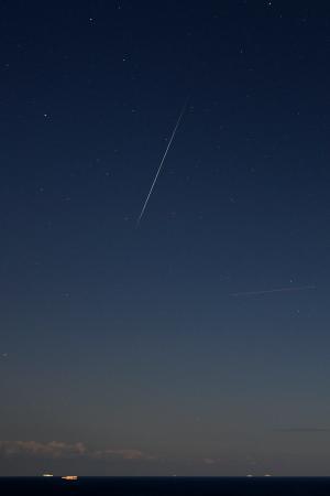 　ふたご座流星群が出現のピークを迎え、宮崎市の堀切峠で見られた流れ星＝１４日未明（２０秒露光）