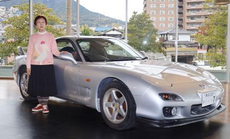 　製造元マツダへの譲渡を前に、愛車「ＲＸ-７」の横に立つ西本尚子さん＝１８日午後、長崎市