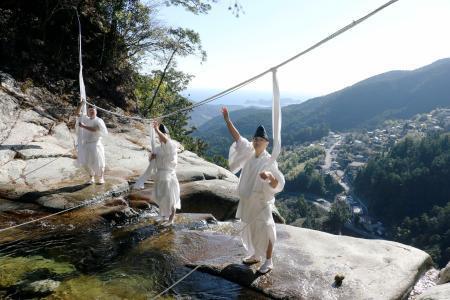 　「那智の滝」の上に架かるしめ縄を張り替える熊野那智大社の神職＝２７日午前、和歌山県那智勝浦町