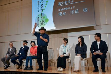 　「ふるさとの光」発見プロジェクトの発表会で、広島県庄原市の魅力をアピールする地元ガイド（中央）ら＝９日午後、広島市南区