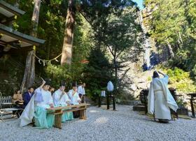 　「那智の滝」（右奥）の前で営まれた、熊野那智大社の「牛王神璽祭」＝８日午前、和歌山県那智勝浦町