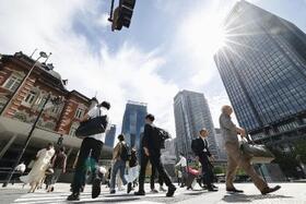 　強い日差しの中、ＪＲ東京駅前を歩く人たち