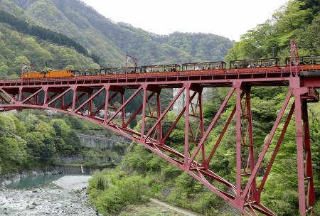 　鉄橋を渡る黒部峡谷鉄道のトロッコ電車＝４月、富山県黒部市