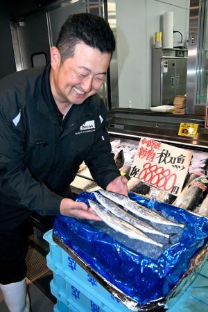 　１匹８万８８８０円の値が付いたサンマを見つめ、笑顔を見せる水産加工会社マルサ笹谷商店の笹谷剛社長＝９日午前、北海道釧路町