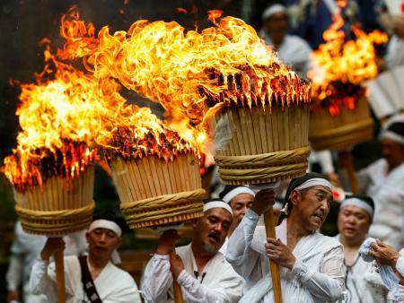 　「那智の扇祭り」で、燃えさかる大たいまつを担ぎ練り歩く白装束の氏子ら＝１４日午後、和歌山県那智勝浦町