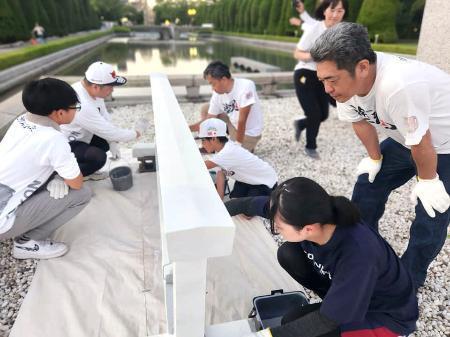 　広島市の平和記念公園で柵を白く塗るボランティア＝２０２５年７月（塗魂ペインターズ事務局提供）