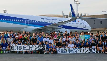 　鳥取空港滑走路でのマラソン大会を終え、記念写真に納まる参加者ら＝１日早朝