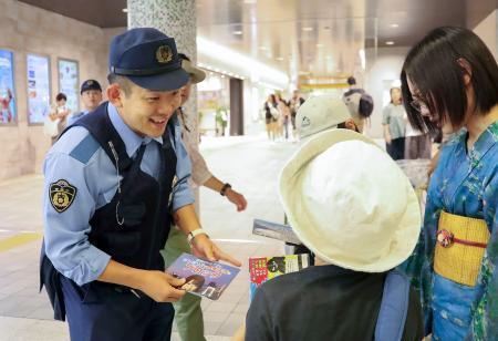 　ＪＲ上野駅構内で詐欺への注意喚起のチラシを配る警視庁の警察官＝４日午前