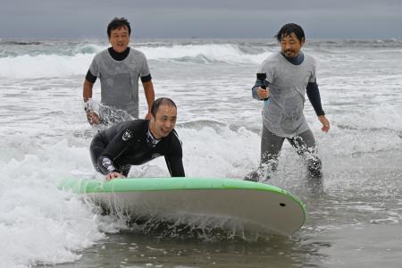 　障害者向けのサーフィン体験会で波に乗る片岡亮太さん＝３０日午前、福島県いわき市の薄磯海岸