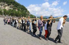 　三重県熊野市の花窟神社で営まれた「お綱かけ神事」でご神体の巨岩から大綱を引く参拝客ら＝２日午前