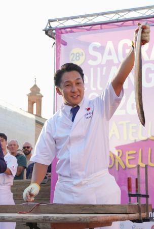　イタリア・コマッキオで開かれたウナギ祭りで、さばいたウナギを見せる田舎庵の緒方仁さん＝３日（共同）