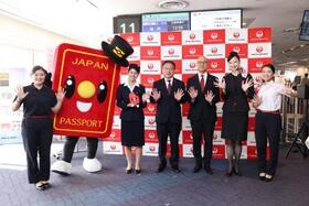 　日本航空と外務省が開いた記念イベントで「パスポくん」と写真に納まる関係者ら＝１７日午後、羽田空港