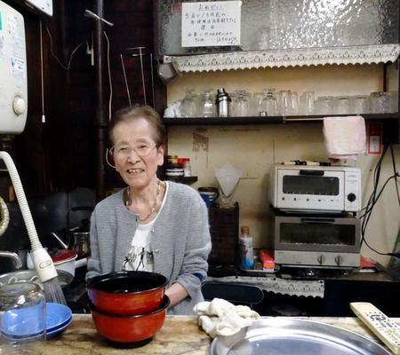 57年間切り盛りした喫茶店のカウンターで笑顔を見せるマコさん。90歳で引退した＝東京・築地場外市場