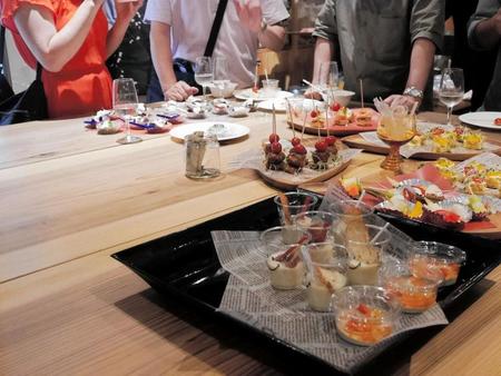大きな正方形のテーブルを囲んで日本酒とフードを楽しむ