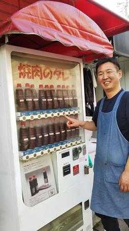 「焼肉のタレ」自販機を紹介する店主の平沼謹郎さん