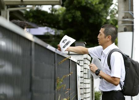 逃走した樋田淳也容疑者の顔写真の入りチラシを住宅街で配る捜査員（提供・共同通信社）