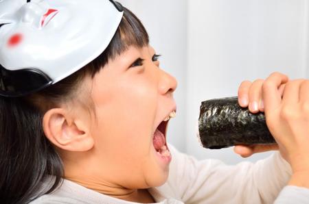 恵方を向いて一気にガブリ（hanapon1002/stock.adobe.com)