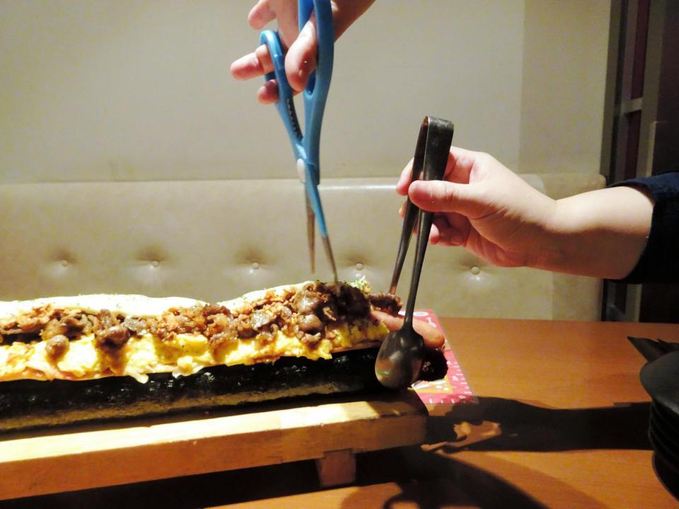 トングで恵方巻の端を抑えてハサミで切る