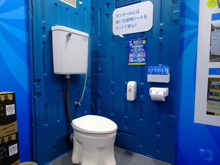 トイレットペーパーの上部に携帯お尻洗浄器が置かれた仮設トイレのモデル＝東京ビッグサイト