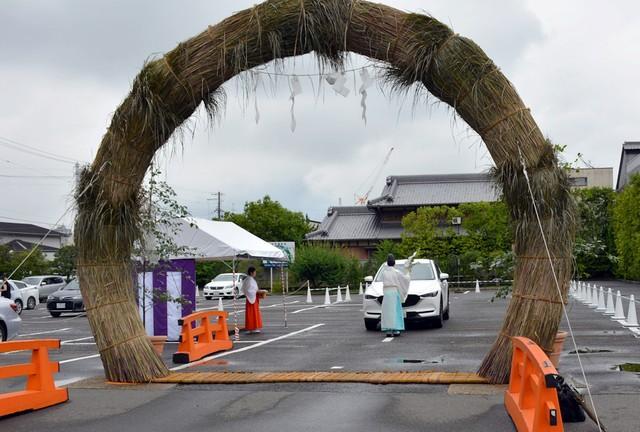 巨大な茅の輪の前で神職のおはらいを受ける車＝京都市伏見区・城南宮