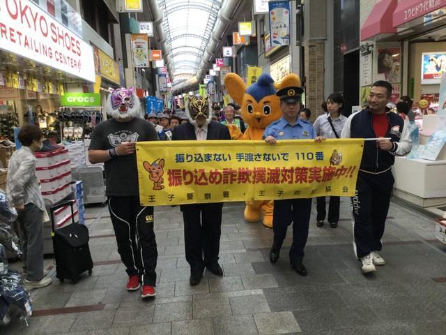 防犯キャンペーンで商店街をパレードする初代タイガーマスク（左から２人目）＝都内の十条銀座商店街