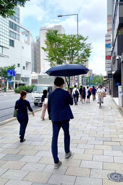 日傘をさして街を歩く男性。熱ストレスから身を守る効果があるという