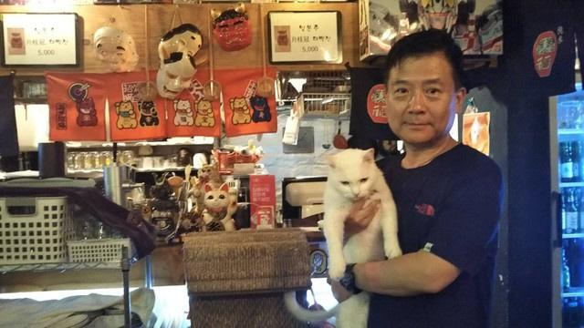 ソウル市内の日本風居酒屋「とんぼ」店主のカン・ナムキュさん。記念撮影で起こされたネコちゃんは不機嫌モード