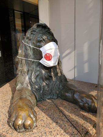 巨大なマスクを着けた銀座三越のライオン像。道行く人が足を止めて撮影していく＝都内